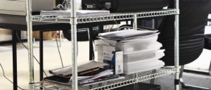A wire stand with a printer sitting on one of the shelves